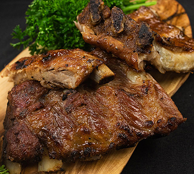 Cooked ribs on wooden board with vegetables