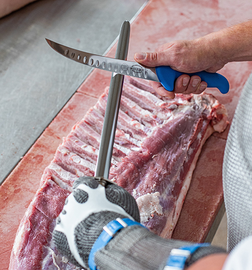 Professional FDick butcher working with a knife and sharpening steel